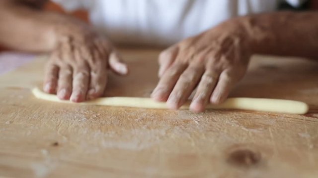 Uomo mezza et&agrave; che sta facendo la pasta fatta in casa su un tagliere di legno.