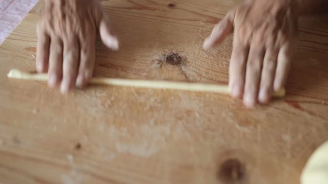 Uomo mezza et&agrave; che sta facendo la pasta fatta in casa su un tagliere di legno.