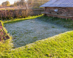 Frost on the grass after the first night frost does not melt for a long time in the shadow of the shed