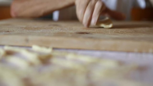 Uomo mezza et&agrave; che sta facendo la pasta fatta in casa su un tagliere di legno.