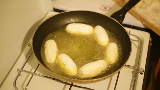 Crocchette di patate ripiene con prosciutto e provola che friggono in padella. 