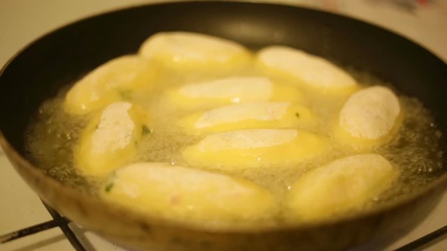 Crocchette di patate ripiene con prosciutto e provola che friggono in padella. 