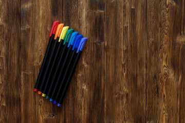 Lots of assorted rainbow colors marker pens, copyspace wooden background