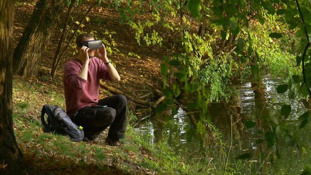 Man Puts on 360Vr Glasses Watching Video 360 Degrees Holding a Smartphone Feels the Game Real Turning His Head Playing Virtual Games in Sunny Day in Park