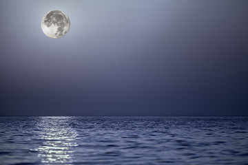 Naklejka na ściany i meble Light from the moon reflecting off a calm blue sea