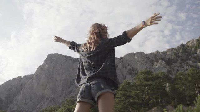Relaxed girl hipster walking on the parapet along the cliffs