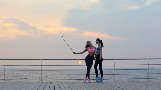 Two young athletic women taking selfie picture after workout at the beach 