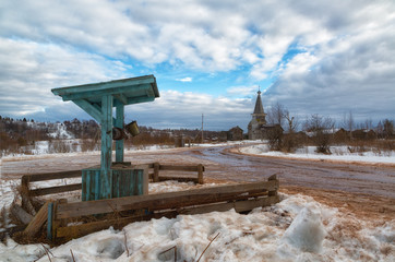 Rural winter landscape with a wooden well in the foreground