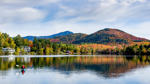 Fototapeta A panoramic view of Mirror Lake in Lake Placid, New York, on a sunny autumn day with colorful fall foliage on the mountains in the background
