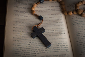 Bible and a rosary with a cross. On a wooden background.Macro. Close up.