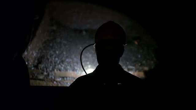 Miner go down into a mine shaft in the elevator cage, silhouette in darkness