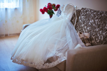 Magnificent wedding dress lies on the couch