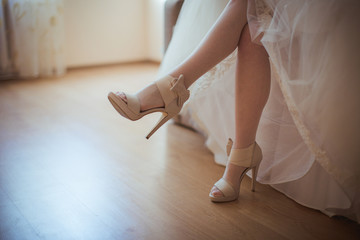 A closeup of seductive bride's legs in beig shoes