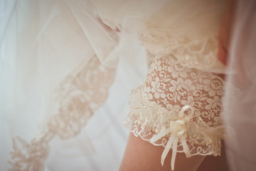 Fototapeta na wymiar A closeup of lace garter on bride's leg under the skirt
