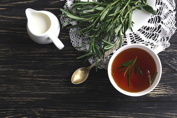 Rosemary tea and milk jar on wooden table.