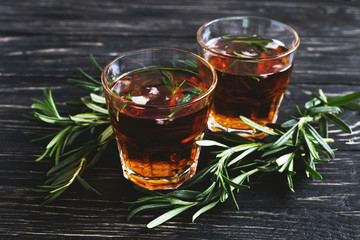 Cold rosemary tea with ice on wooden table