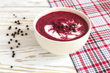 Hot cream beet soup with spices on a wooden background