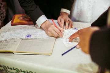 Groom in black suit signs wedding papers