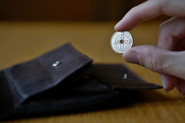 Male hand holding a silver Norwegian coin (currency in Norway, Norwegian krone, NOK) and...