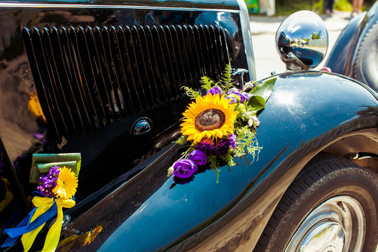 Yellow and violet flowers decorate old black car