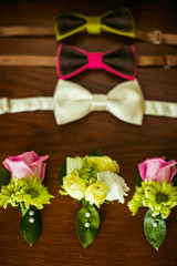 Bright bow ties and boutonnieres lie on the wooden table