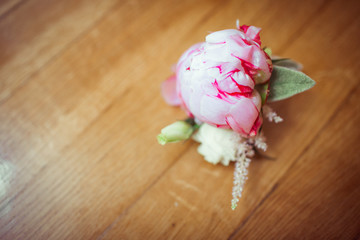 Pink peony lies on the wooden floor