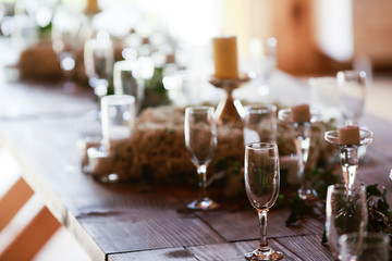 Sun light illuminates a wooden table full of empty glasses and w