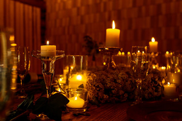 Candles' light illuminates a wooden dinner table
