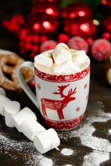 Hot chocolate or cocoa beverage with cinnamon and gingerbread cookies in snowon vintage wooden table background.