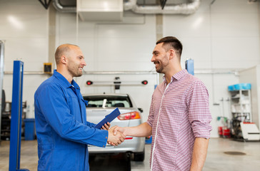 auto mechanic and man shaking hands at car shop
