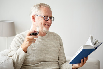 happy senior man drinking wine and reading book