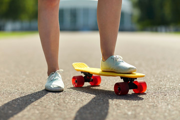 close up of female feet riding short skateboard