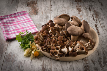 Misto di funghi freschi su un piatto tondo in legno su un tavolo 