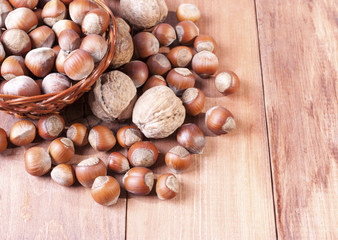 Walnuts and hazelnuts in a basket on wooden background