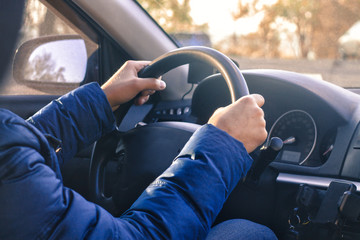 Man starts driving a car. Hand are on wheel. Sunny day