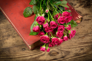 Bouquet of pink roses on old book at wooden table