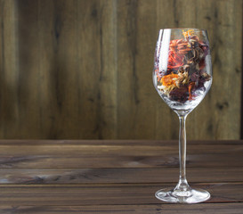 Autumn leaves in a wine glass on wooden table background