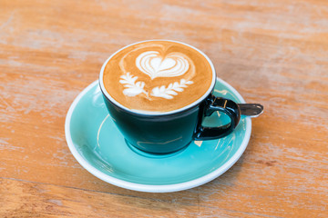 A Cup of hot latte art coffee on wooden table
