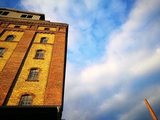 Alter Getreidespeicher und Lagerhaus aus rotbraunem Backstein im Licht der Abendsonne vor blauem...