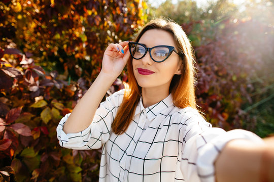 Autumn selfie portrait of a beautiful girl in glasses.