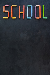 Text "School" created with oil pastels on slate