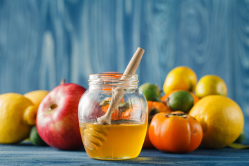 Apple and honey on wooden table over blue background