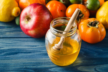Apple and honey on wooden table over blue background