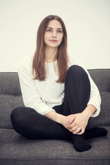 Obraz premium young woman sitting on couch and smiles