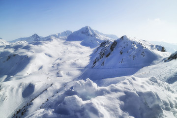 Fototapeta na wymiar Winter snow view of French Alps mountain range with ski slopes and lifts