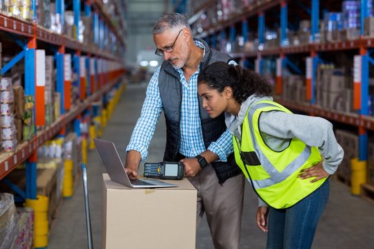 Warehouse workers discussing with laptop
