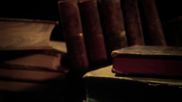Old, aged books on a wooden table. Camera panning and moving.