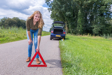 Dutch woman placing warning triangle on rural road
