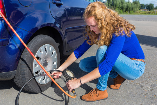 Woman checking air pressure of car tire