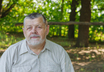 Outdoor portrait of comfortable senior man in light shirt